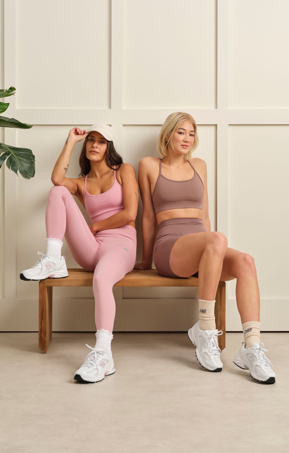 Two women sitting on a bench, wearing new balance 530s
